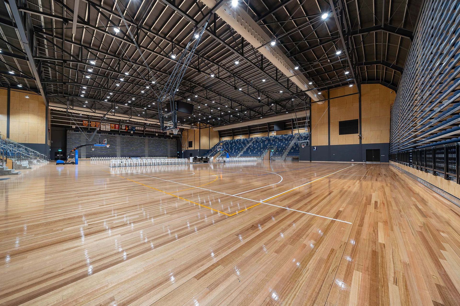 A large indoor basketball court with a wooden floor and bleachers.
