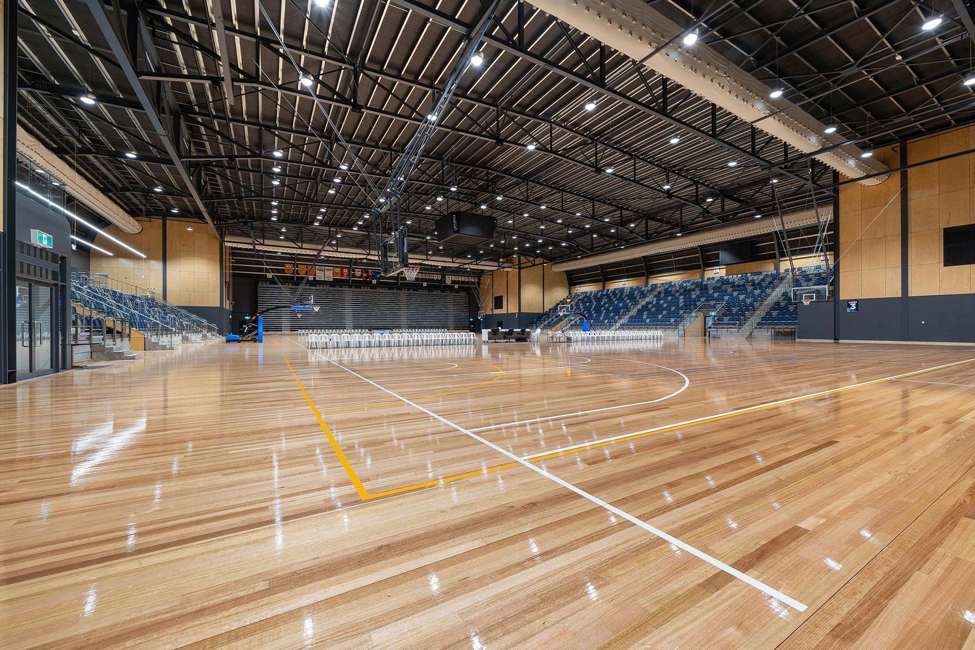 A large indoor basketball court with a wooden floor and bleachers.