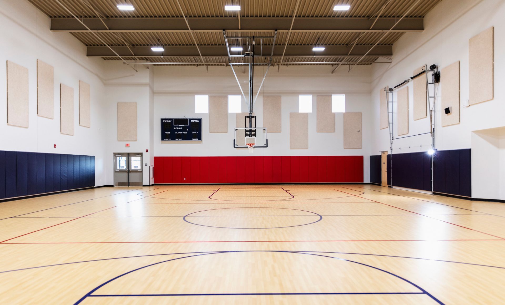 An empty school gymnasium with a basketball court.