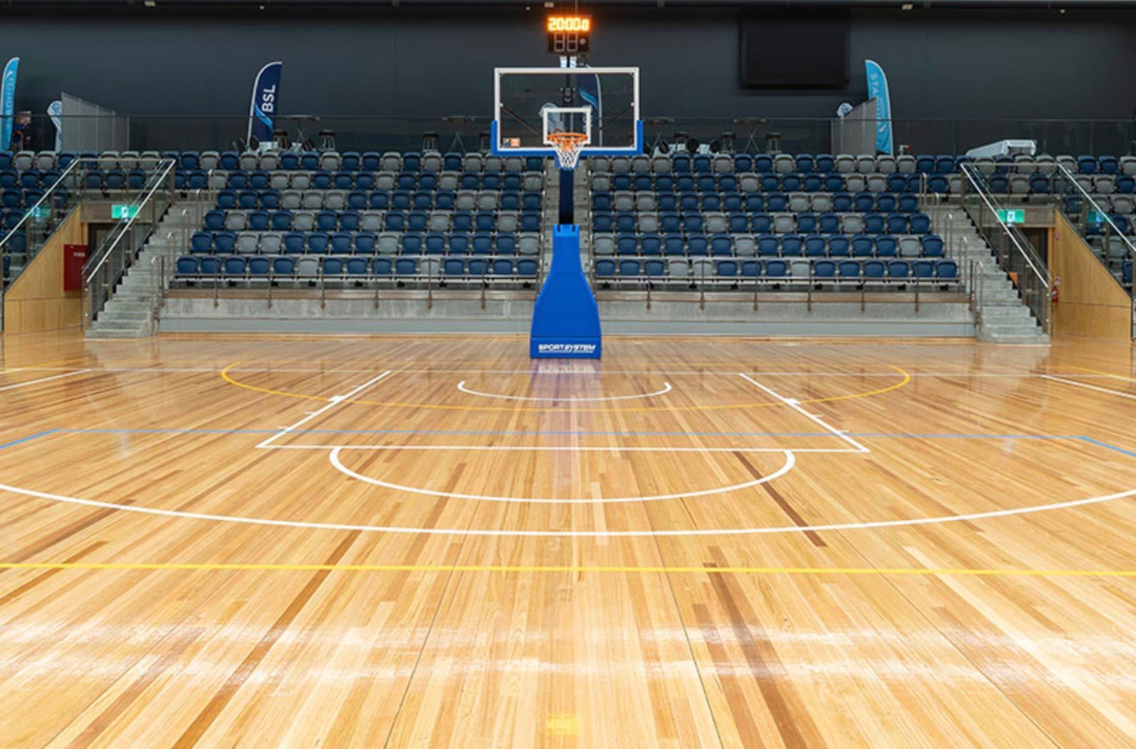 An empty basketball court with a wooden floor and a basketball hoop.
