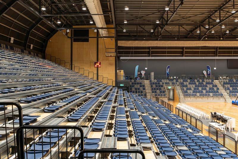An empty stadium with rows of blue seats and a fence.
