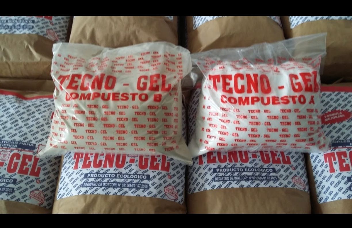 Bolsas TECNO-GEL COMPOSTO blancas y rojas apiladas sobre un fondo de estera tejida.