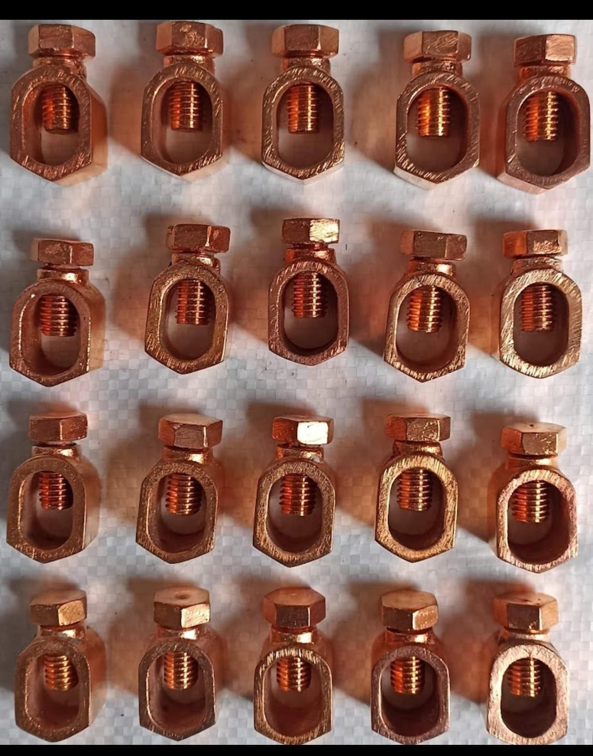 Filas de pequeñas botellas de vidrio ámbar con corchos sobre tela blanca, vistas desde arriba.