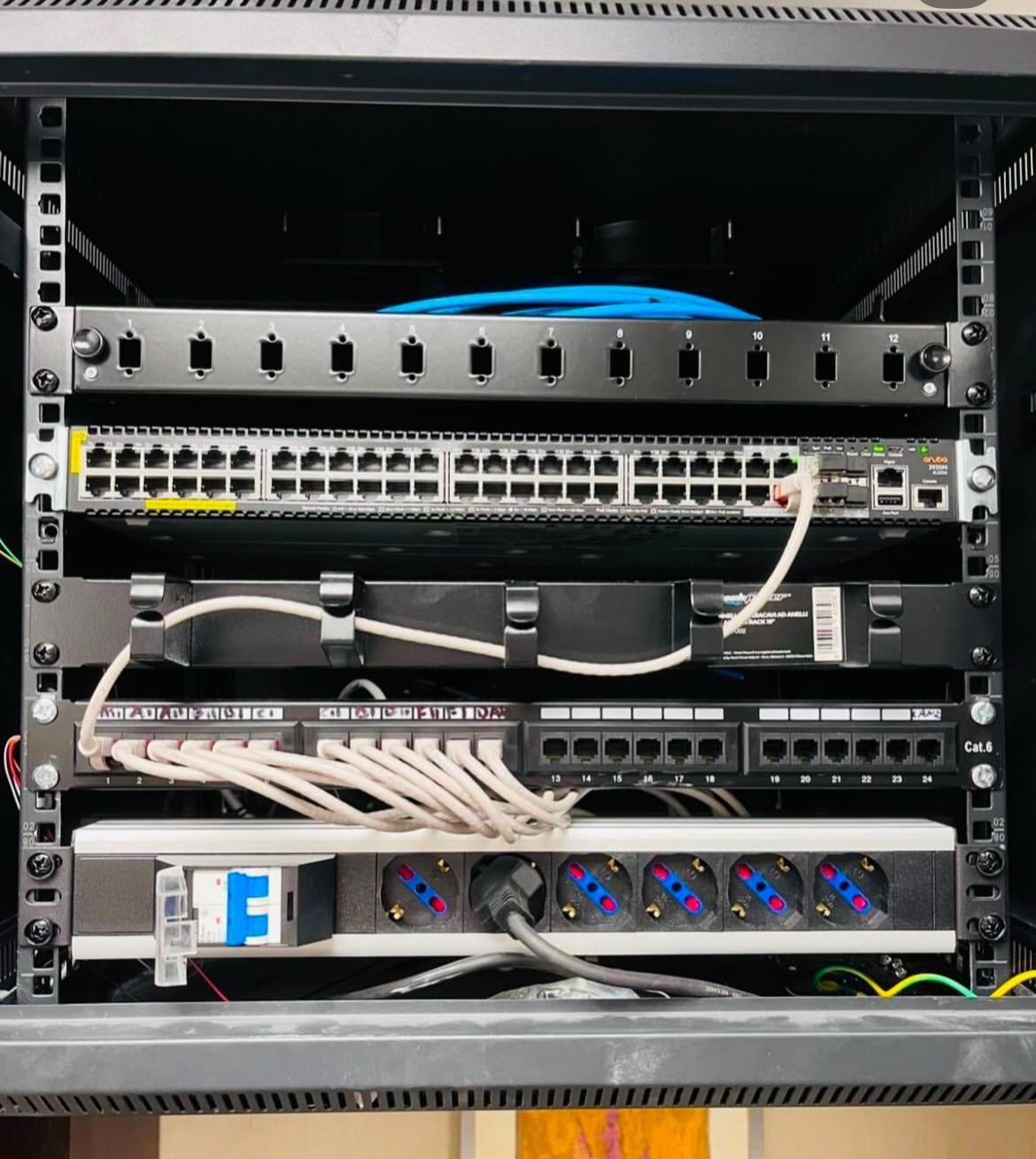 Sala server di rete piena di cavi Ethernet blu. I cavi sono collegati a diversi pannelli neri.