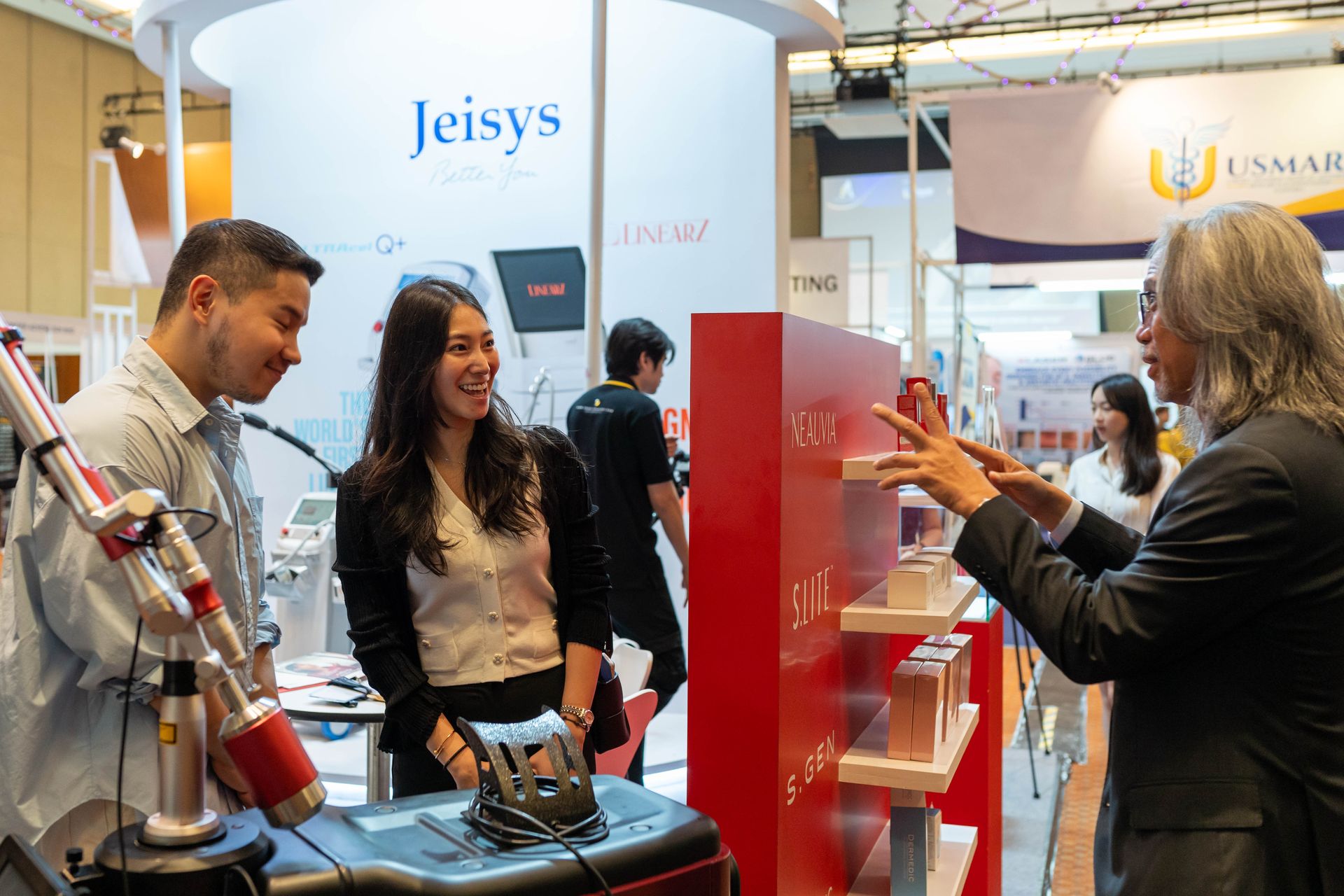 People at a booth, discussing medical equipment, possibly a trade show.