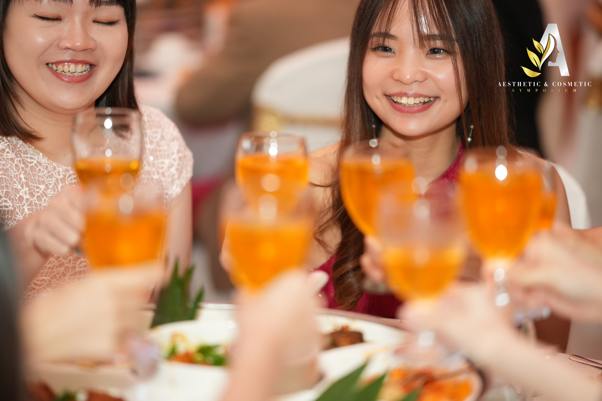 People toasting with orange drinks at a celebratory event, smiling.