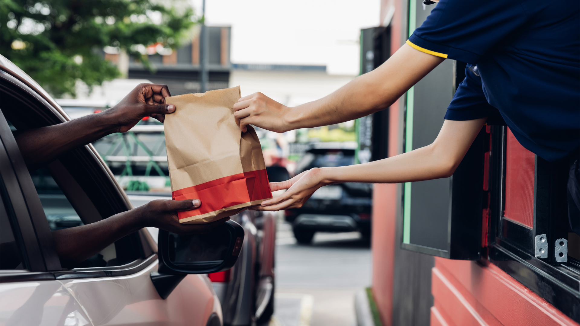 A person is handing a bag of food to another person in a car.