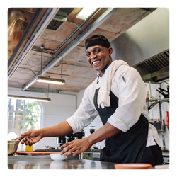 A man in an apron is preparing food in a kitchen