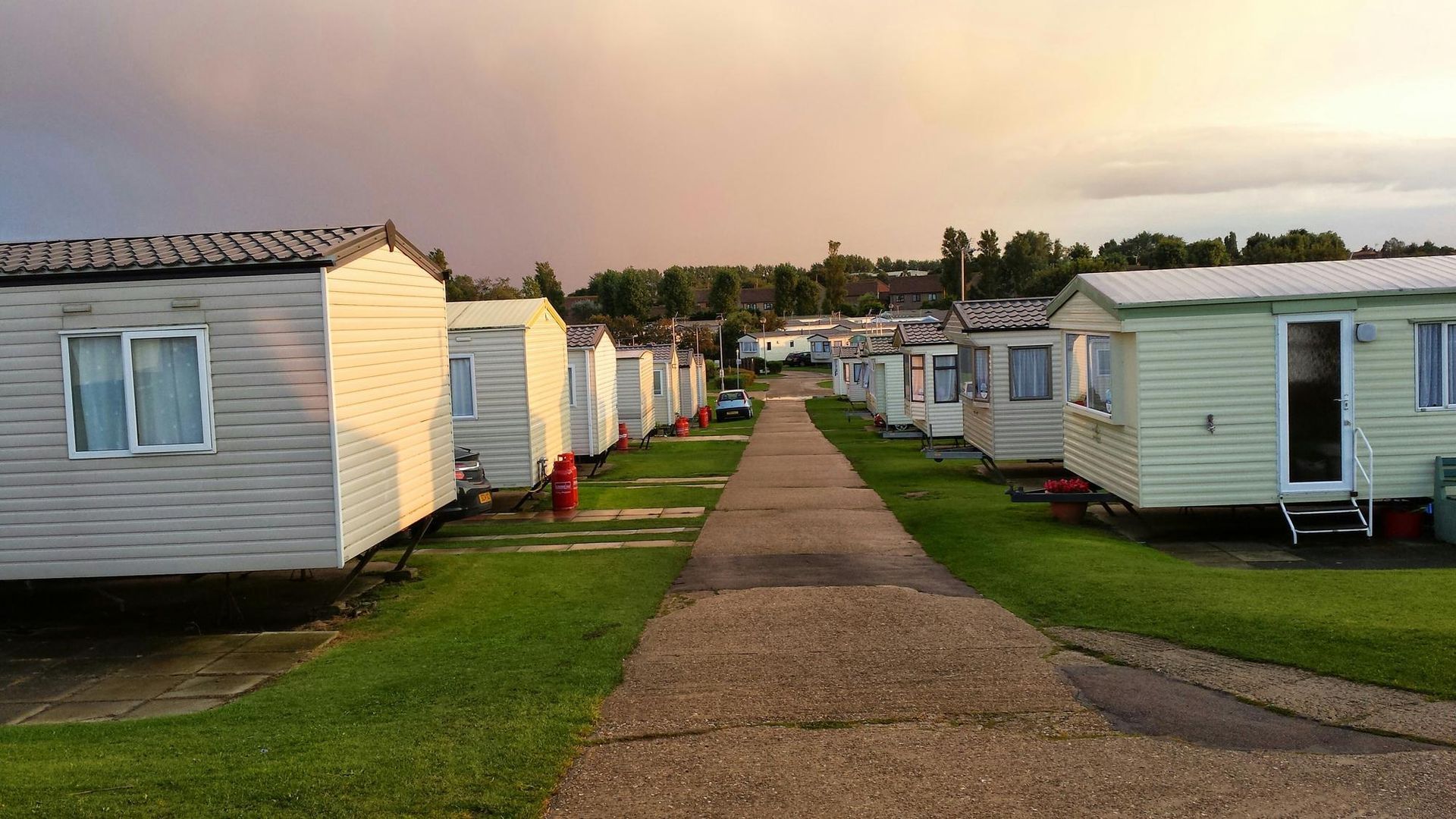 A row of mobile homes are parked next to each other on a dirt road.