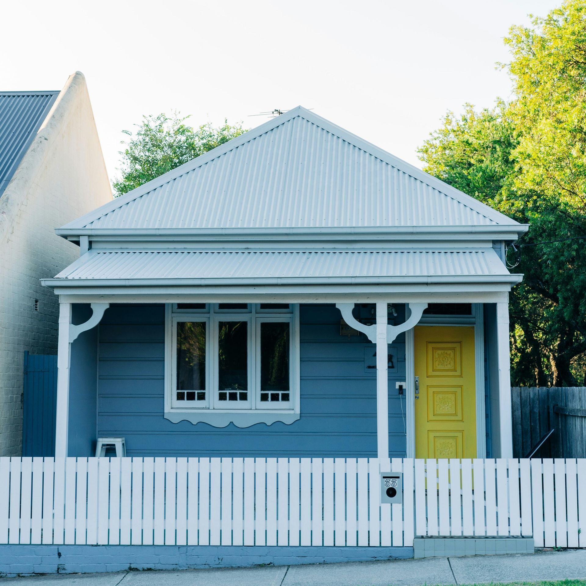 A blue house with a yellow door and a white picket fence