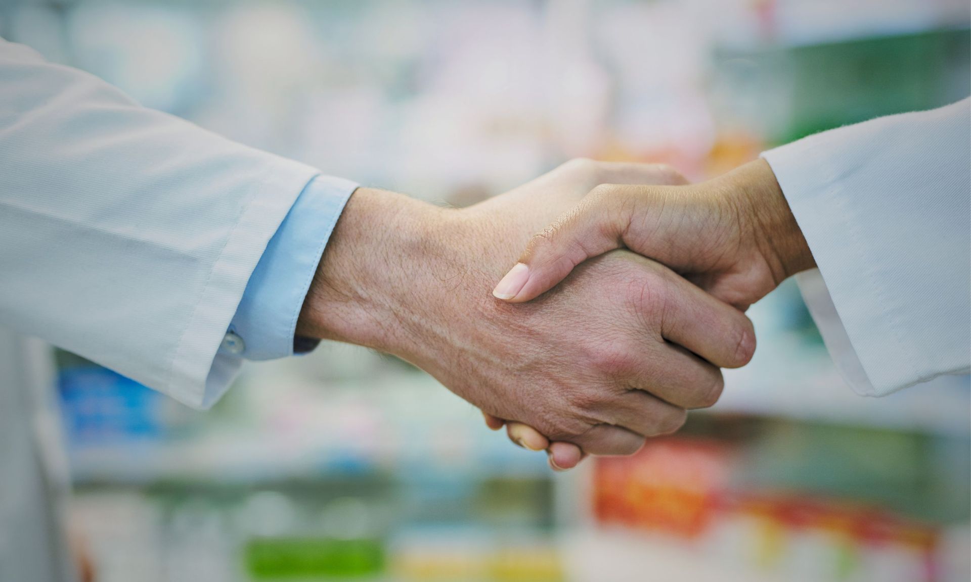 Adapt Ideations works with the pharmaceutical industry as a collaborator and partner. A doctor and a pharmacist are shaking hands in a pharmacy.