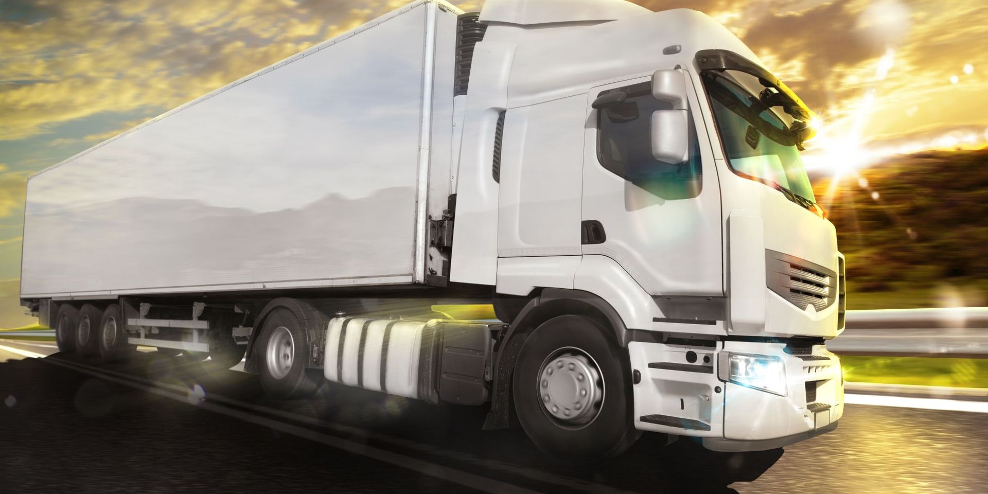 Effective cold chain management can decrease transportation expenses A white semi truck is driving down a highway at sunset.