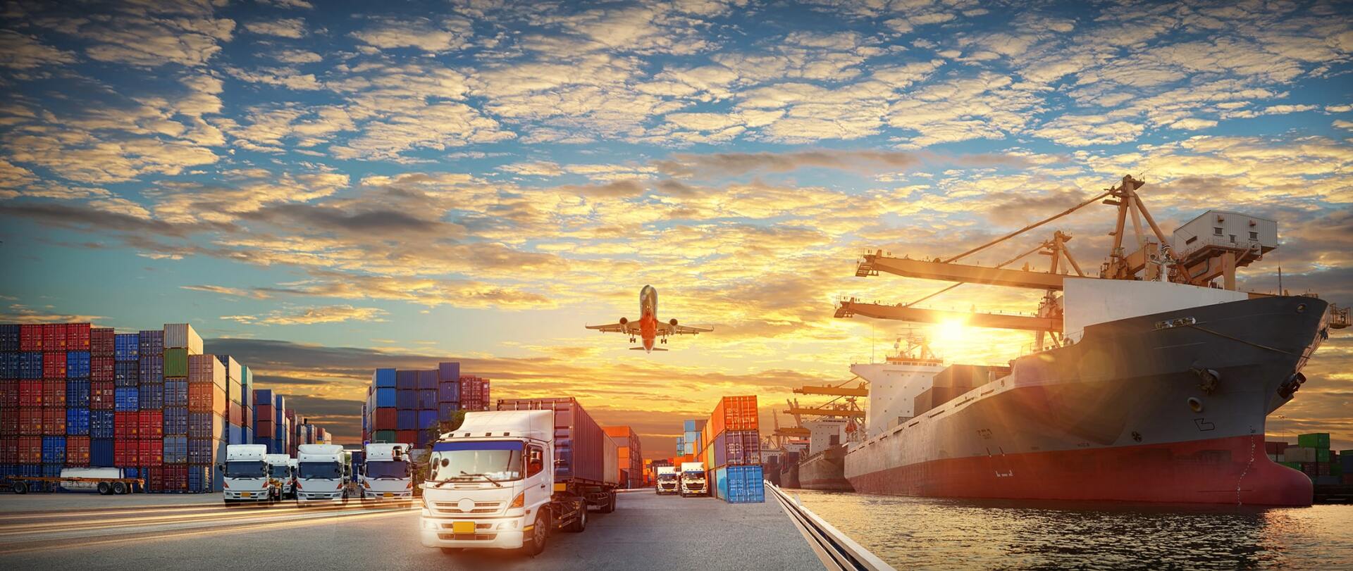 A cargo ship is docked at a port with trucks driving down the road.