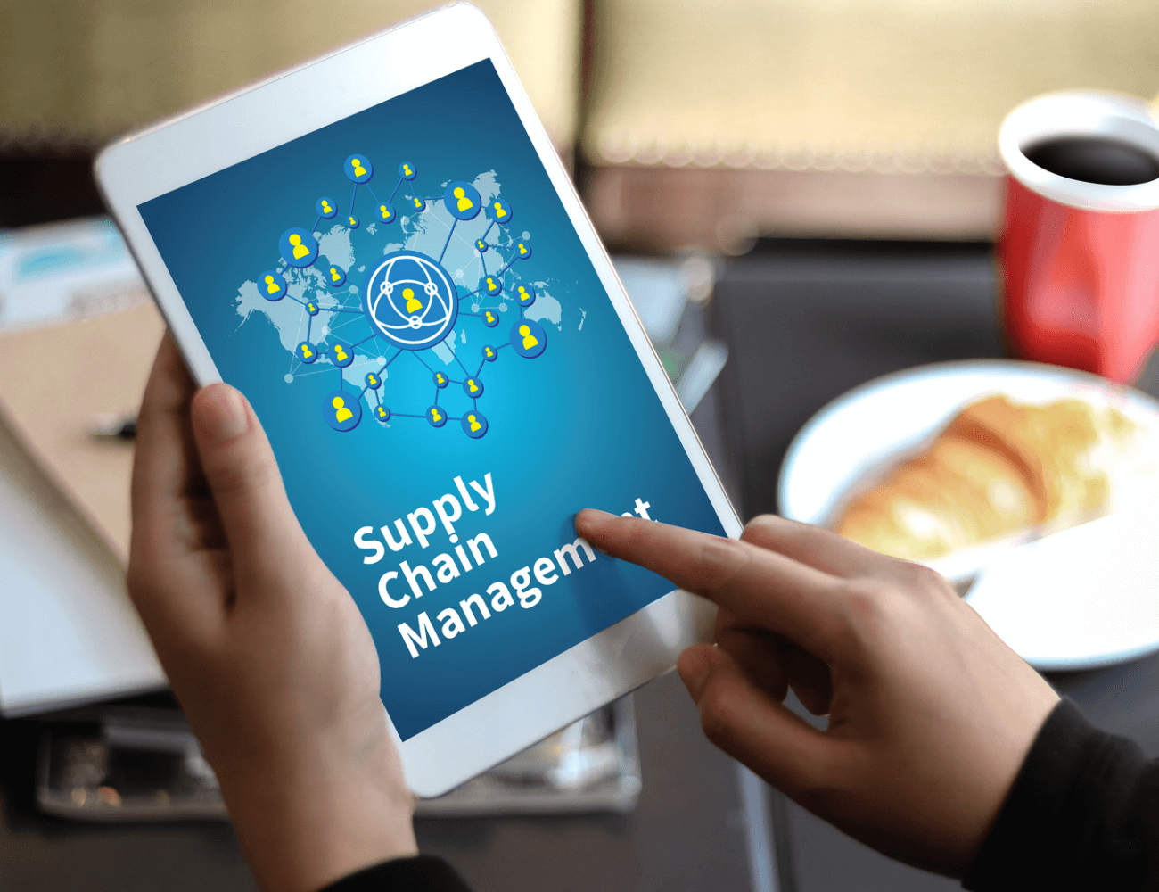 A person is holding a tablet with supply chain management on the screen.
