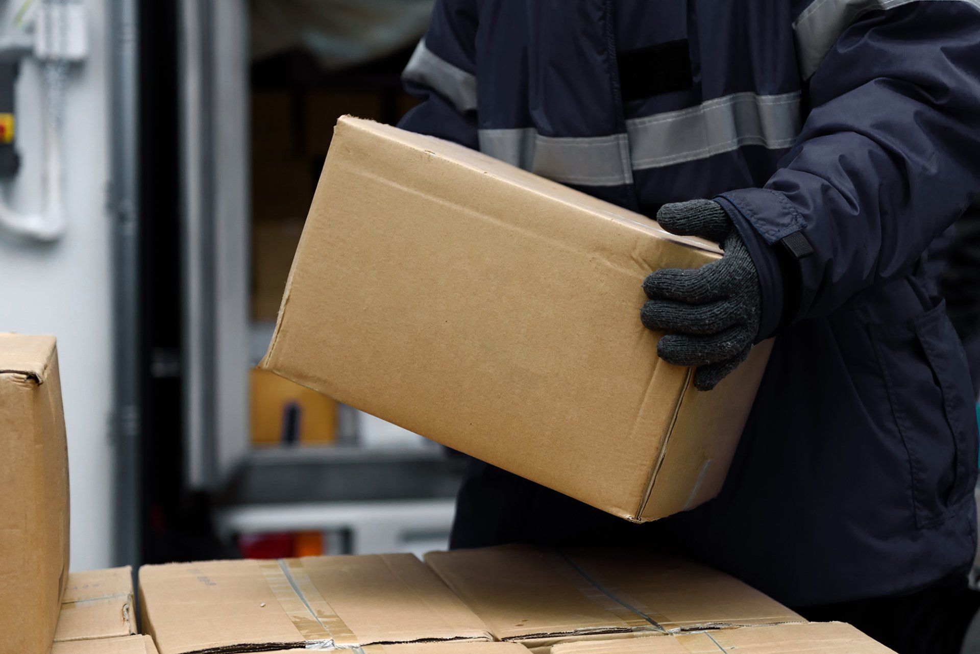 Cold Chain Logistics A man in a blue jacket is holding a cardboard box.