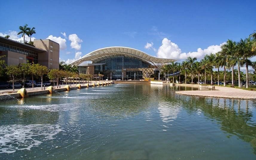 A large building is surrounded by palm trees and a body of water
