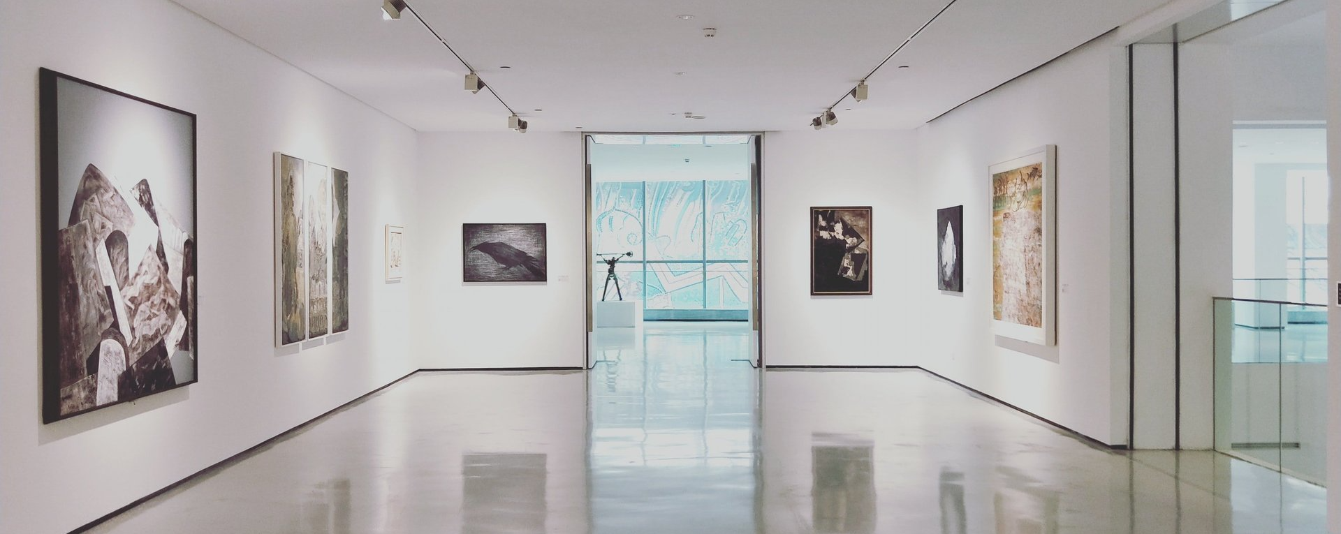 A long hallway in a museum with paintings on the wall.