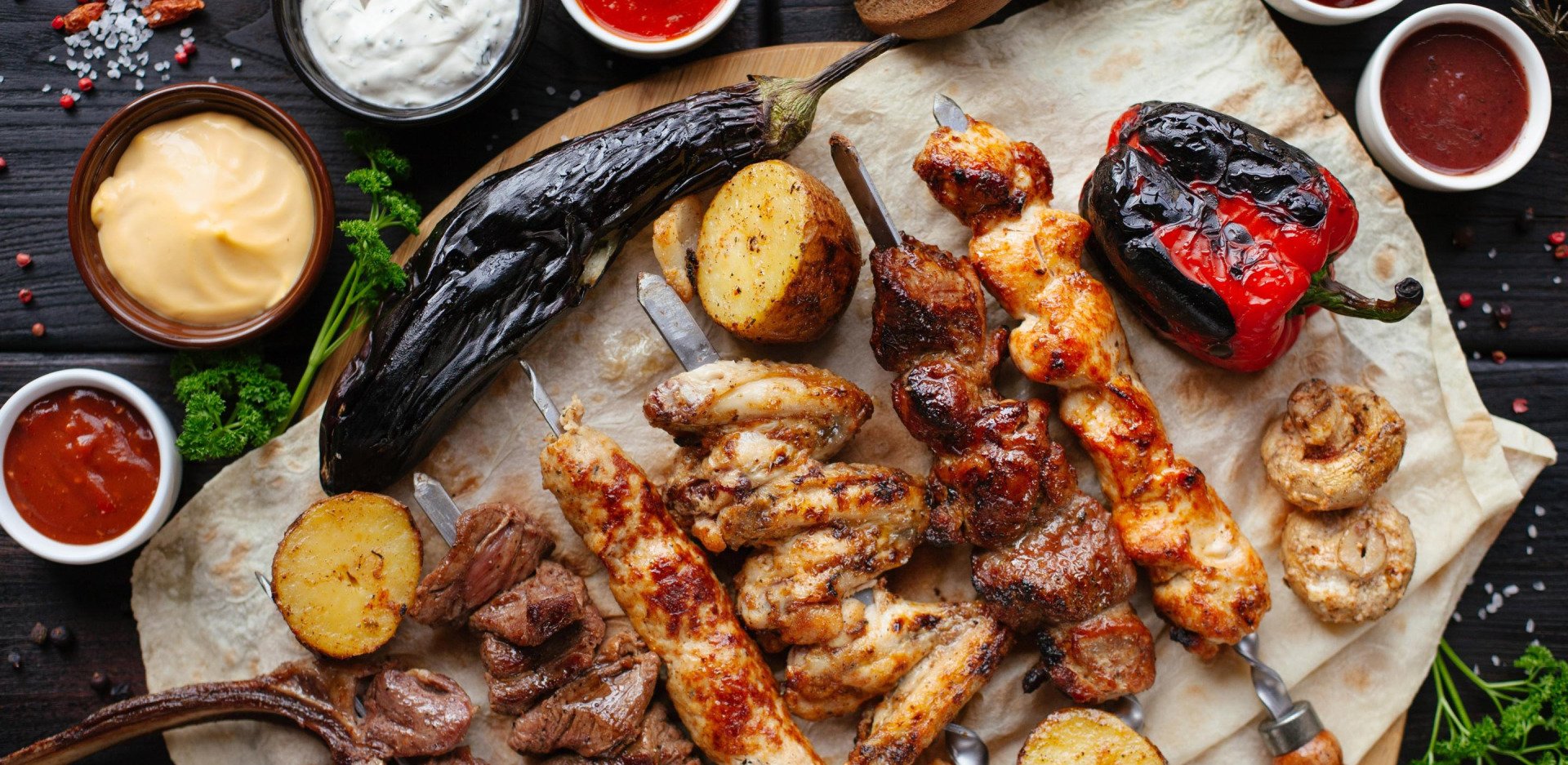A variety of grilled meats and vegetables on a cutting board.