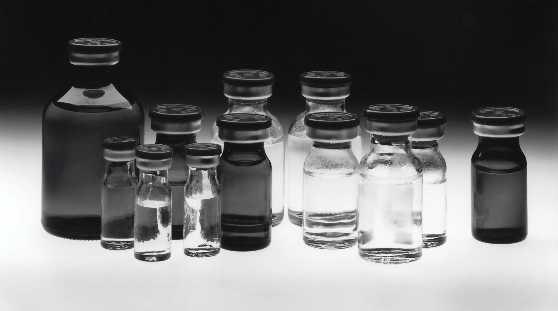 A black and white photo of a group of bottles