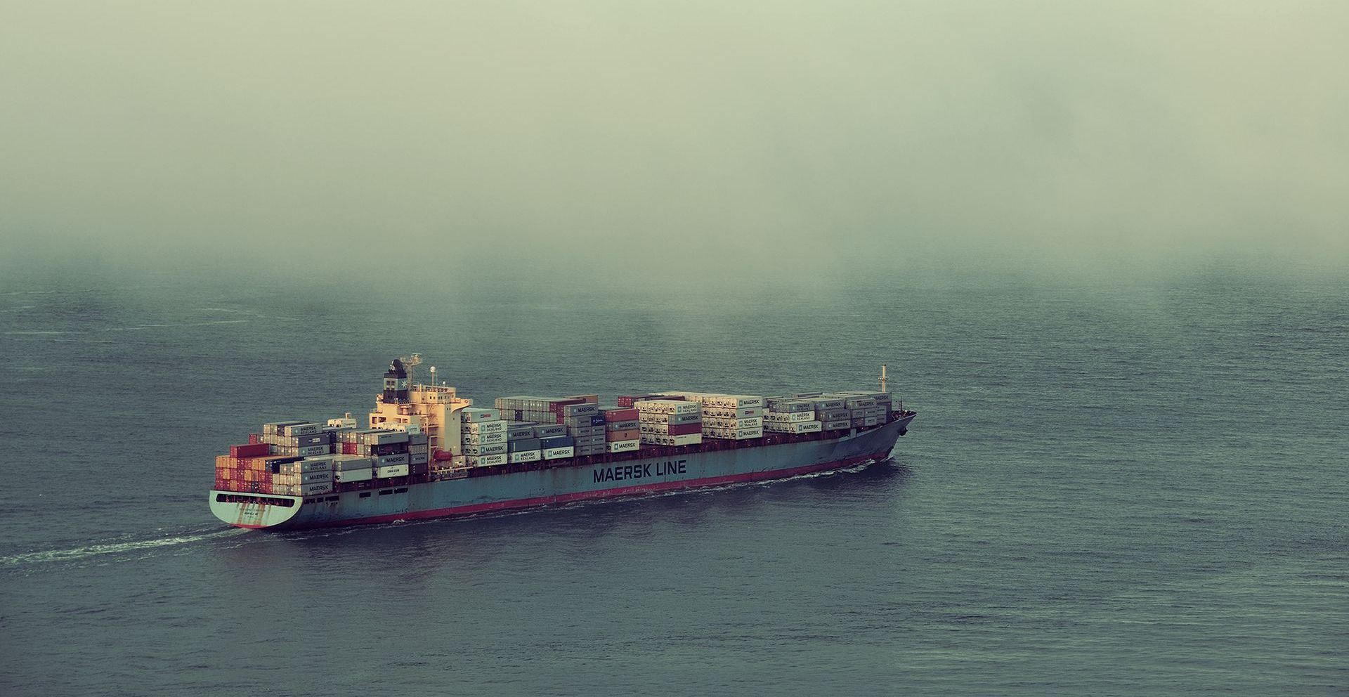 A large container ship is floating on top of a large body of water.