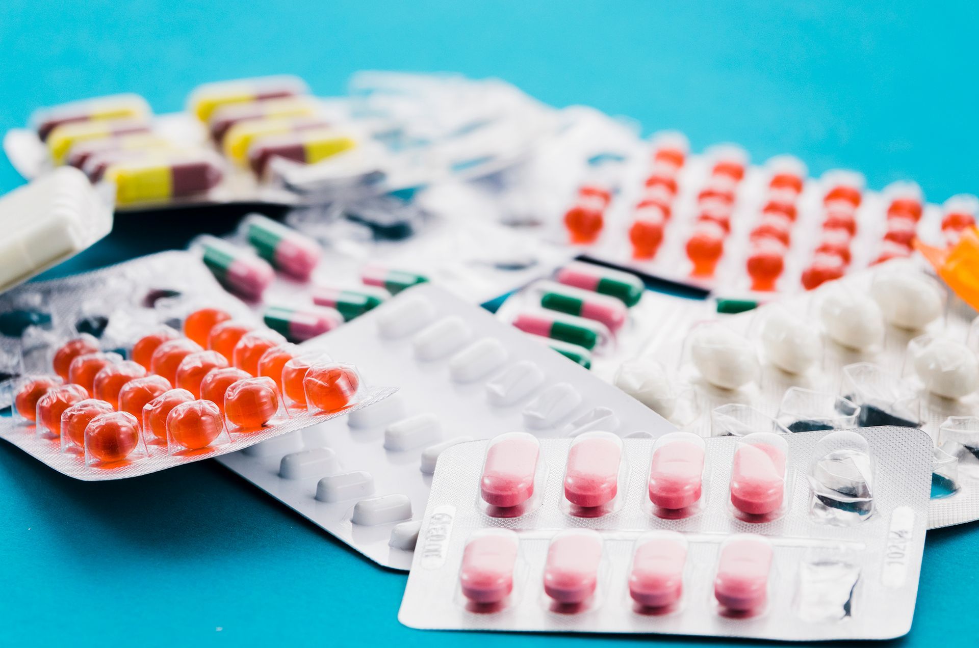 Tablets A bunch of different types of pills in blister packs on a blue background.