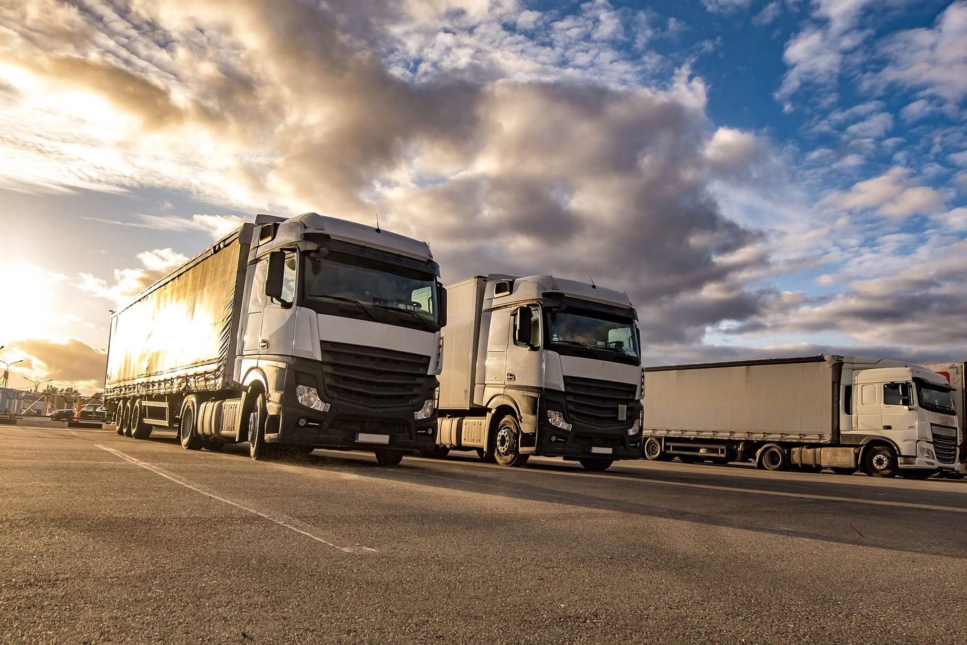 A row of semi trucks are parked on the side of the road.