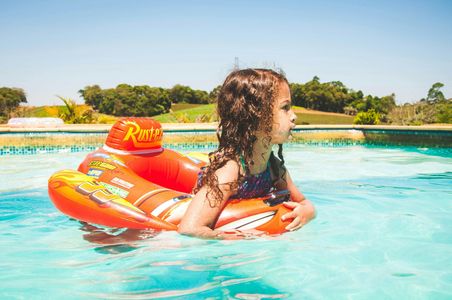 A little girl is floating on an inflatable raft in a swimming pool.