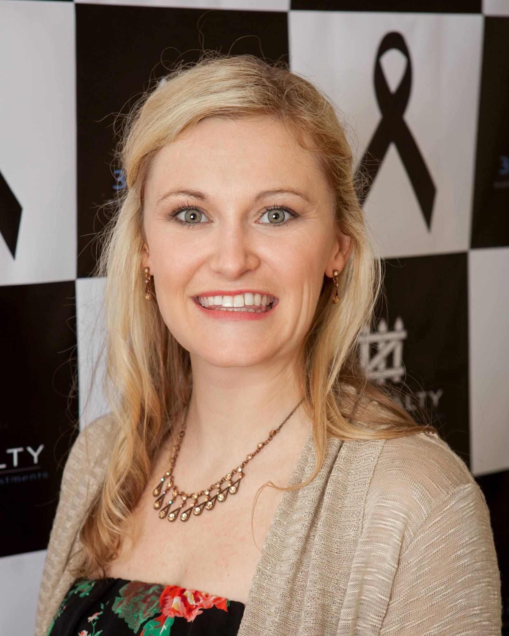 A woman is smiling in front of a black and white checkered background