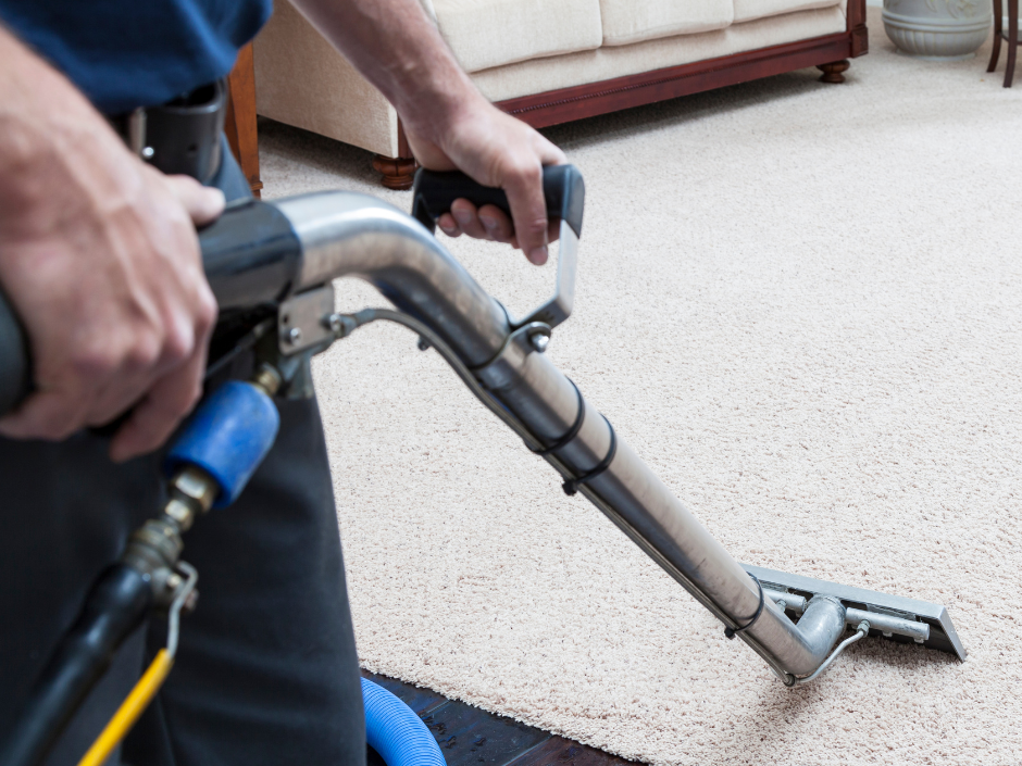 A man is using a vacuum cleaner to clean a carpet in a living room.