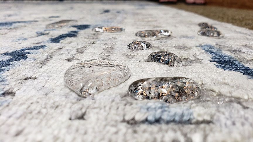 Close-up of glittering water droplets on a white textured surface with dark blue markings