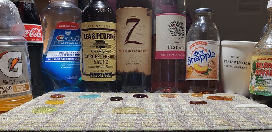 Assorted liquor bottles lined up on a shelf behind a patterned tablecloth.