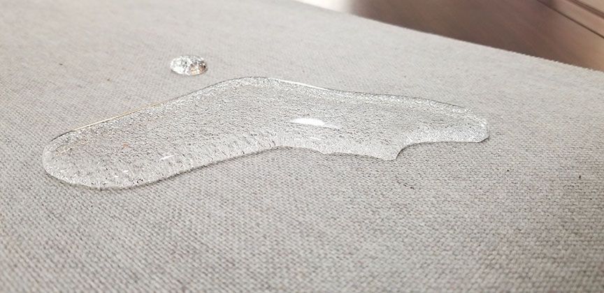 Clear liquid spill on a textured beige carpet