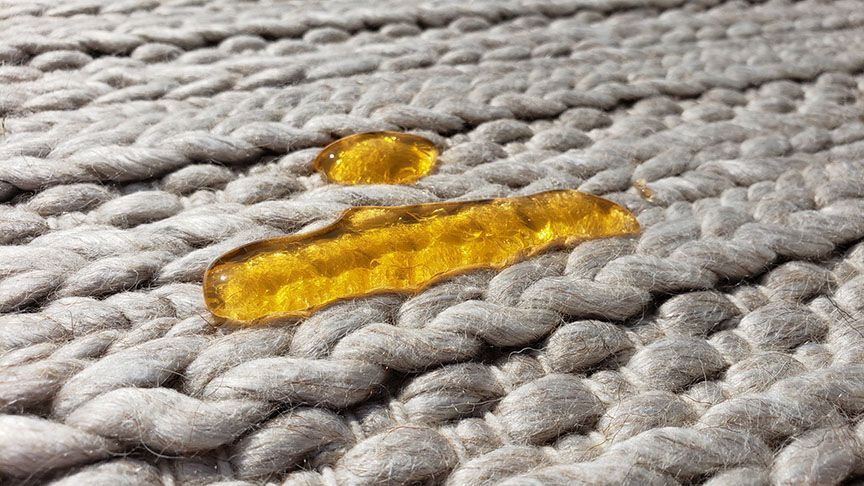 Yellow liquid spilled on a gray knitted fabric surface