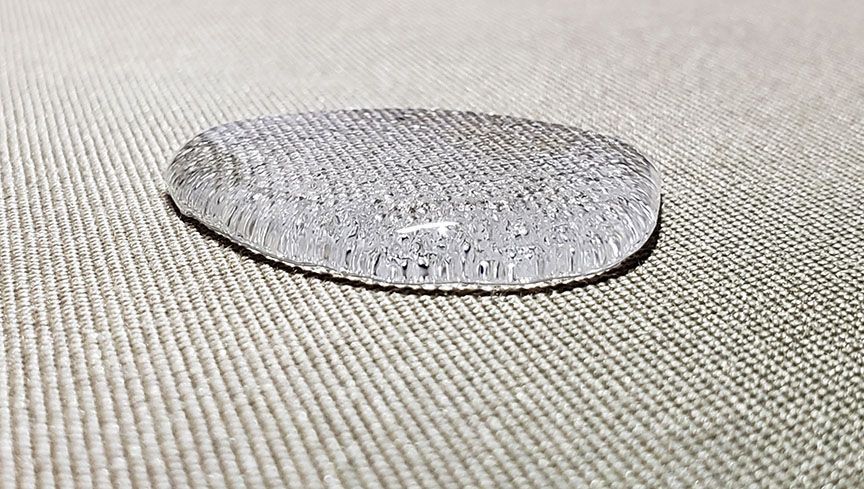 Small round silver textured object resting on a beige fabric surface