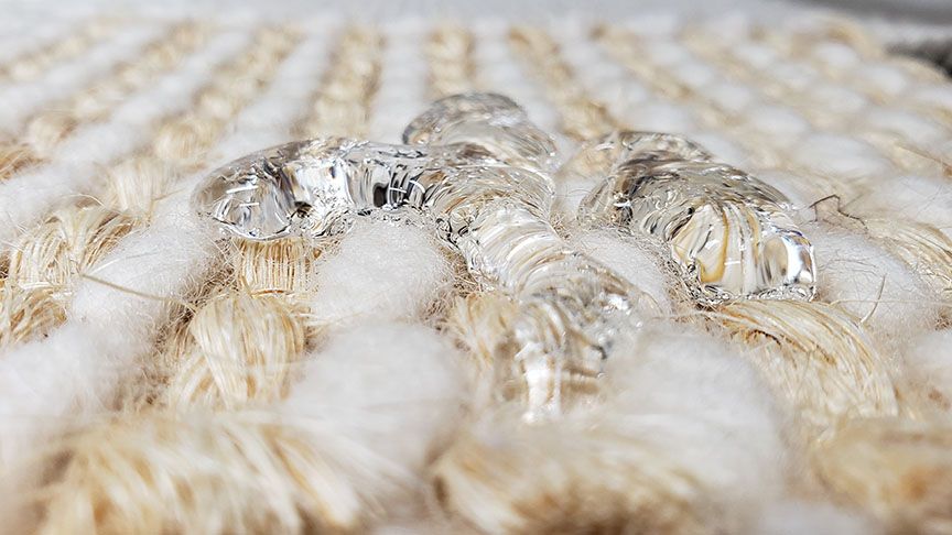 Clear ice crystals on a beige woven fabric surface
