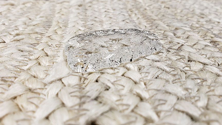 Clear droplet on beige woven fabric close-up