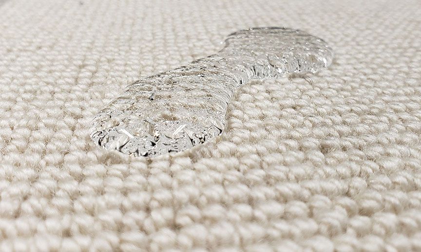 Clear water droplets on a beige woven fabric surface