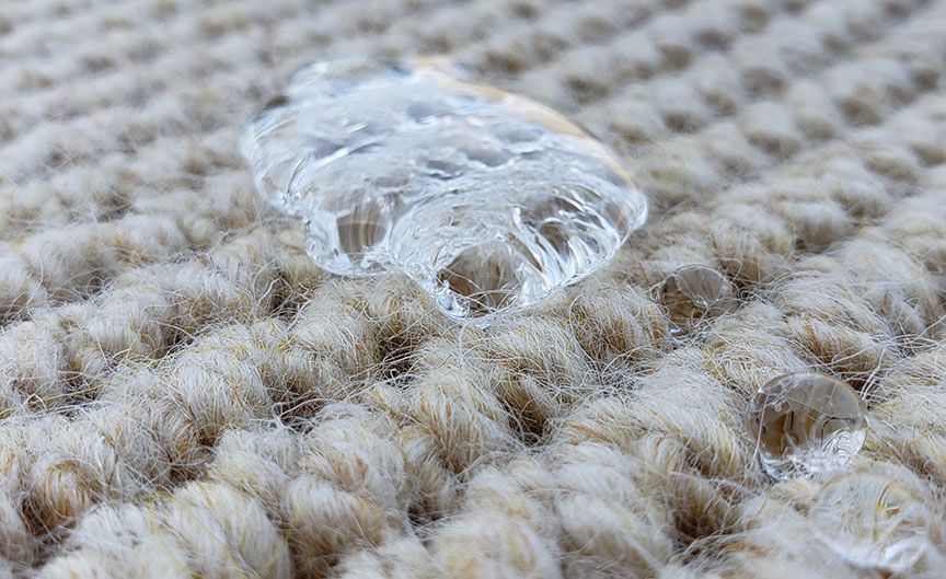 Clear ice cube on beige woven fabric close-up