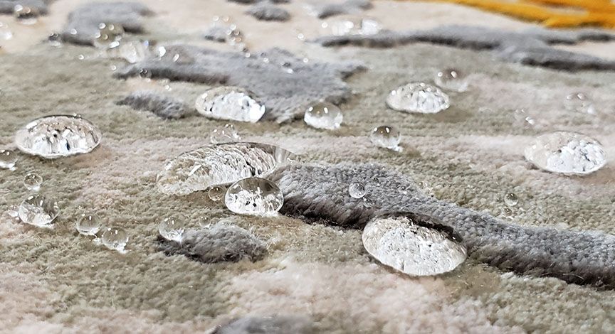 Close-up of clear raindrops on a wet concrete surface with a yellow line in the background