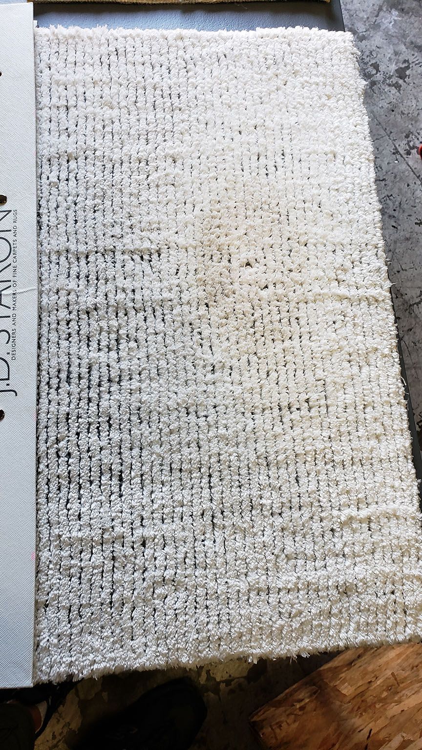 Close-up of a light beige textured woven rug or mat on the floor.