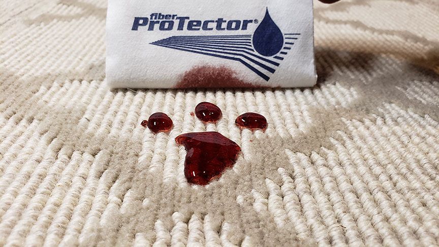 White ProTector pad with dark red blood droplets on a beige textured surface.