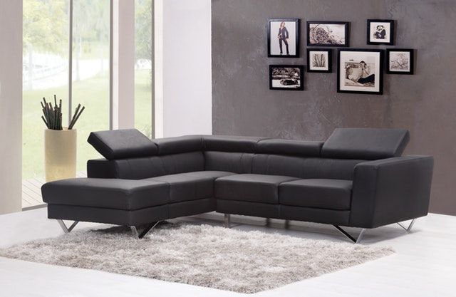 Modern black sectional sofa in a bright living room with wall art and a shag rug