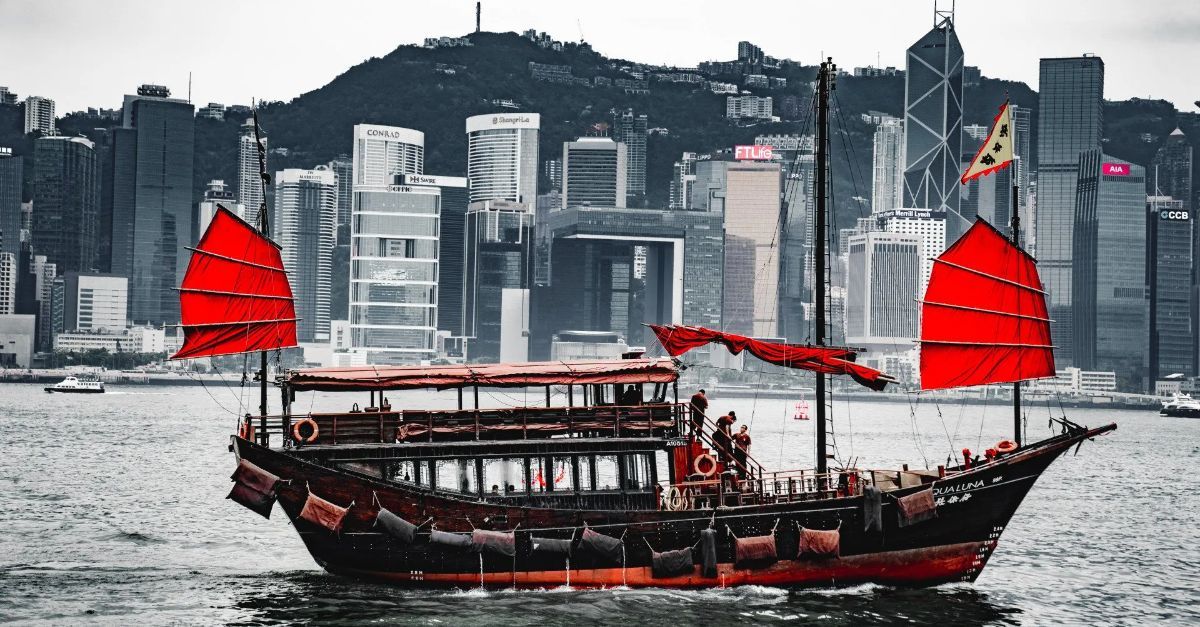 A boat with red sails is floating on top of a body of water.