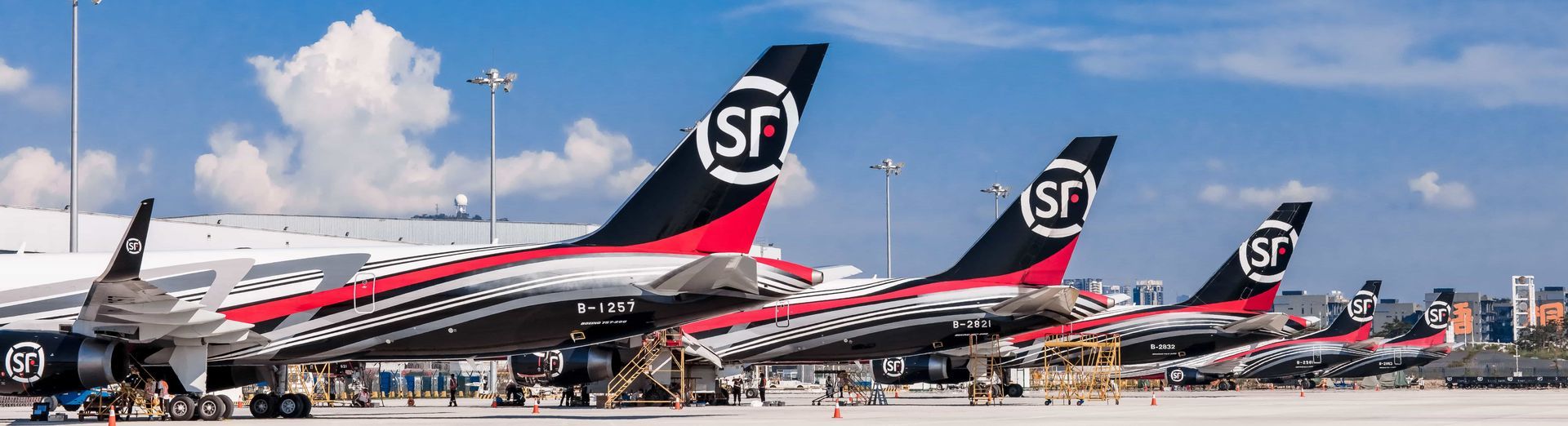 A row of planes are parked on the tarmac at an airport.