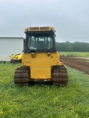 A yellow Caterpillar bulldozer parked in a grassy field on an overcast day.