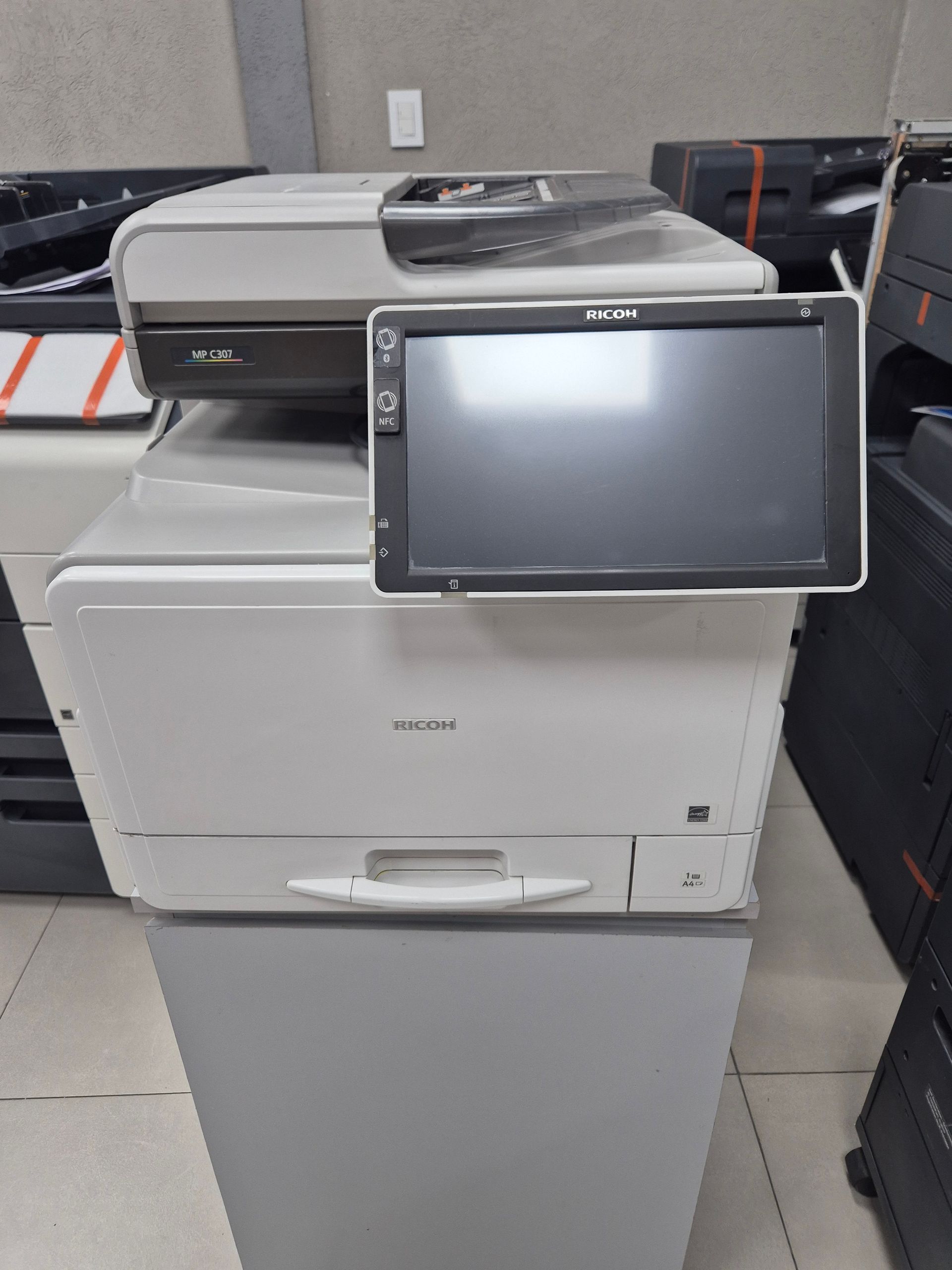 Fotocopiadora de oficina blanca con panel de control táctil en un entorno de almacenamiento o exposición.