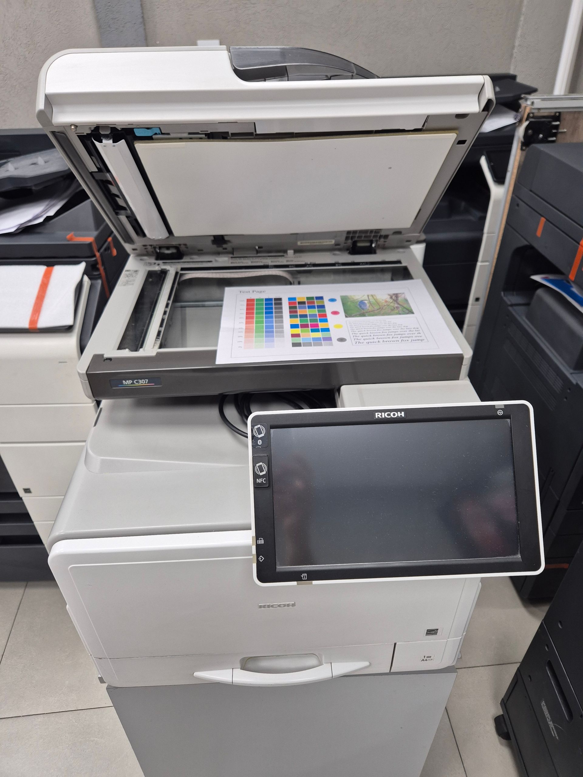 Fotocopiadora de oficina blanca con panel de control táctil en un entorno de almacenamiento o exposición.