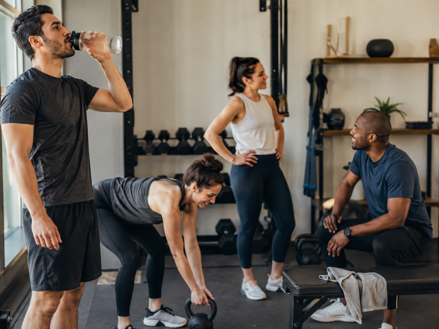 Small group of gym members talking and recovering together after a workout.