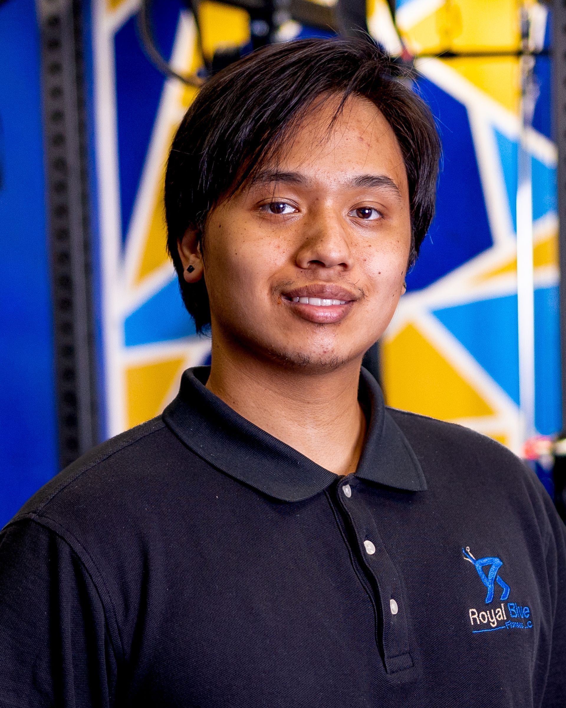Kennedy Rizon, fitness trainer at Royal Blue Fitness, smiling in gym