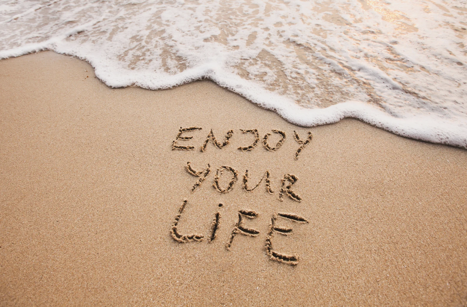 Enjoy your life message written in beach sand